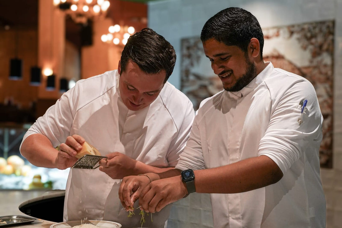 Twee koks in witte Cheffix-koksbuizen werken samen een gerecht af